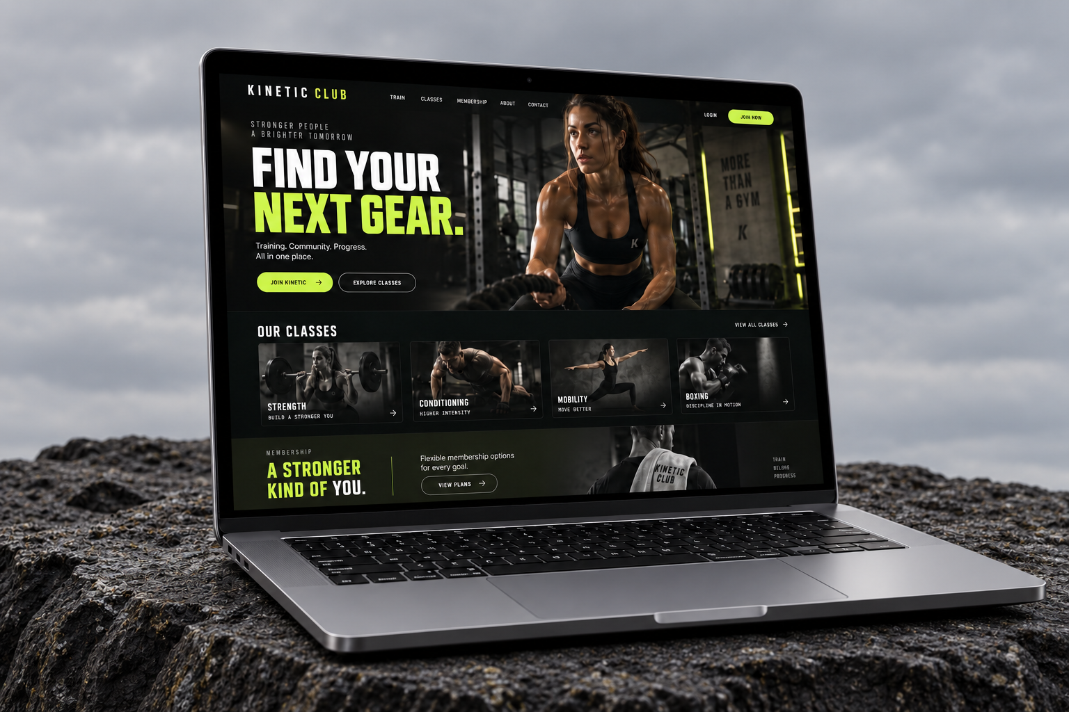 Kinetic Club landing page displayed on a MacBook on a dark basalt rock shelf